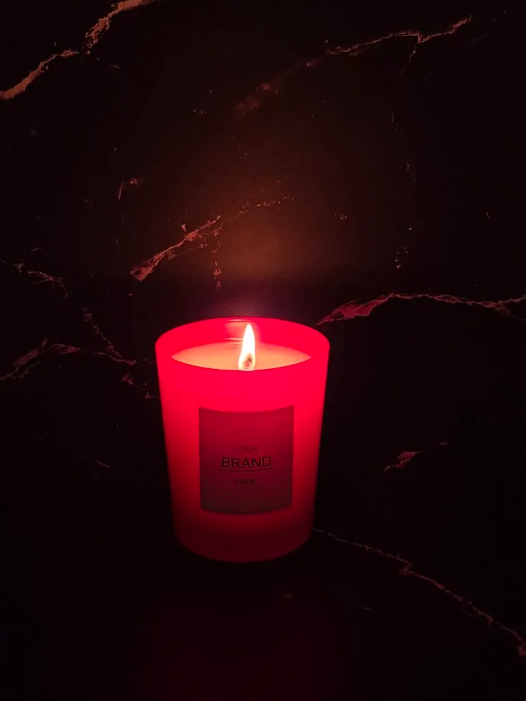 Vela perfumada roja encendida sobre mármol oscuro
